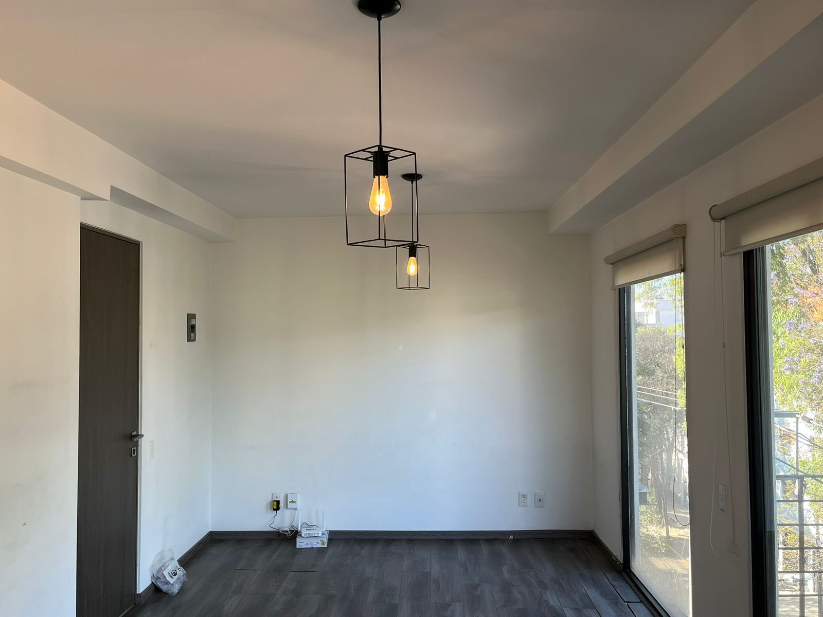 Sala iluminada con ventanales grandes y lámparas colgantes modernas.
