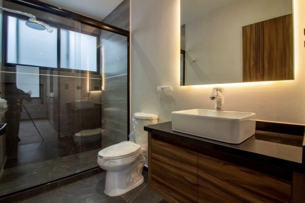 Baño moderno con espejo iluminado y acabados en mármol.
