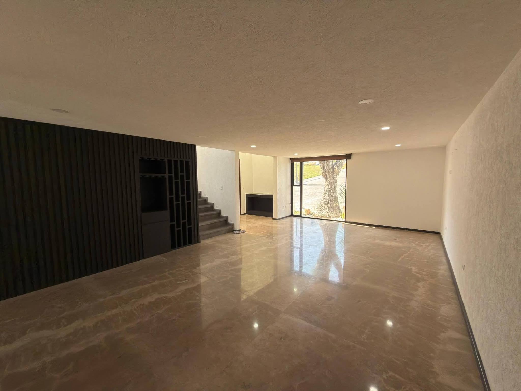 Sala con acabados modernos y ventana amplia que proporciona luz natural.