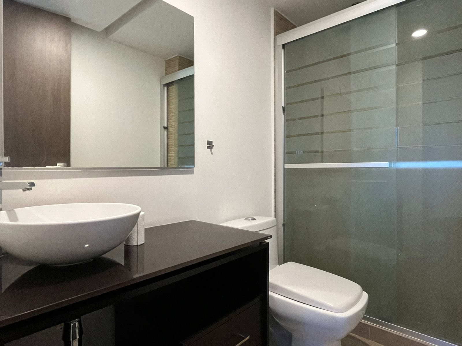 Baño moderno con lavabo de diseño y ducha de vidrio templado.