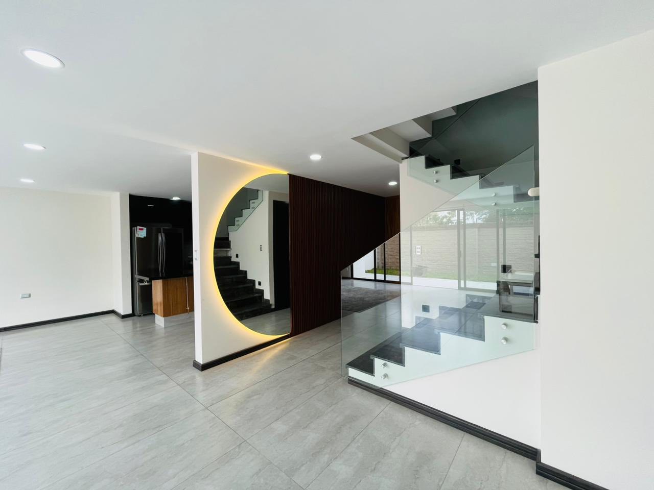 Sala amplia con iluminación LED indirecta y escaleras de cristal que dan un toque sofisticado.
