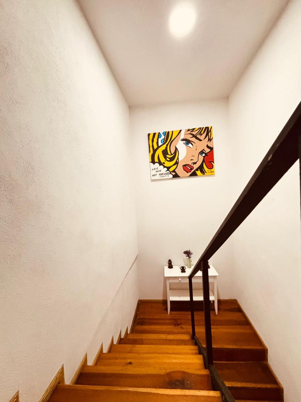 Escaleras bien iluminadas con acabados de madera, conectan las áreas del departamento.