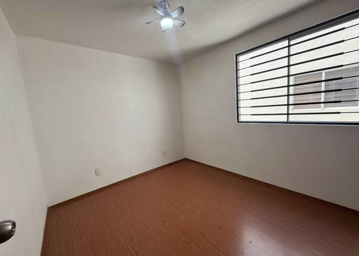 Recámara con piso laminado y ventilador de techo.