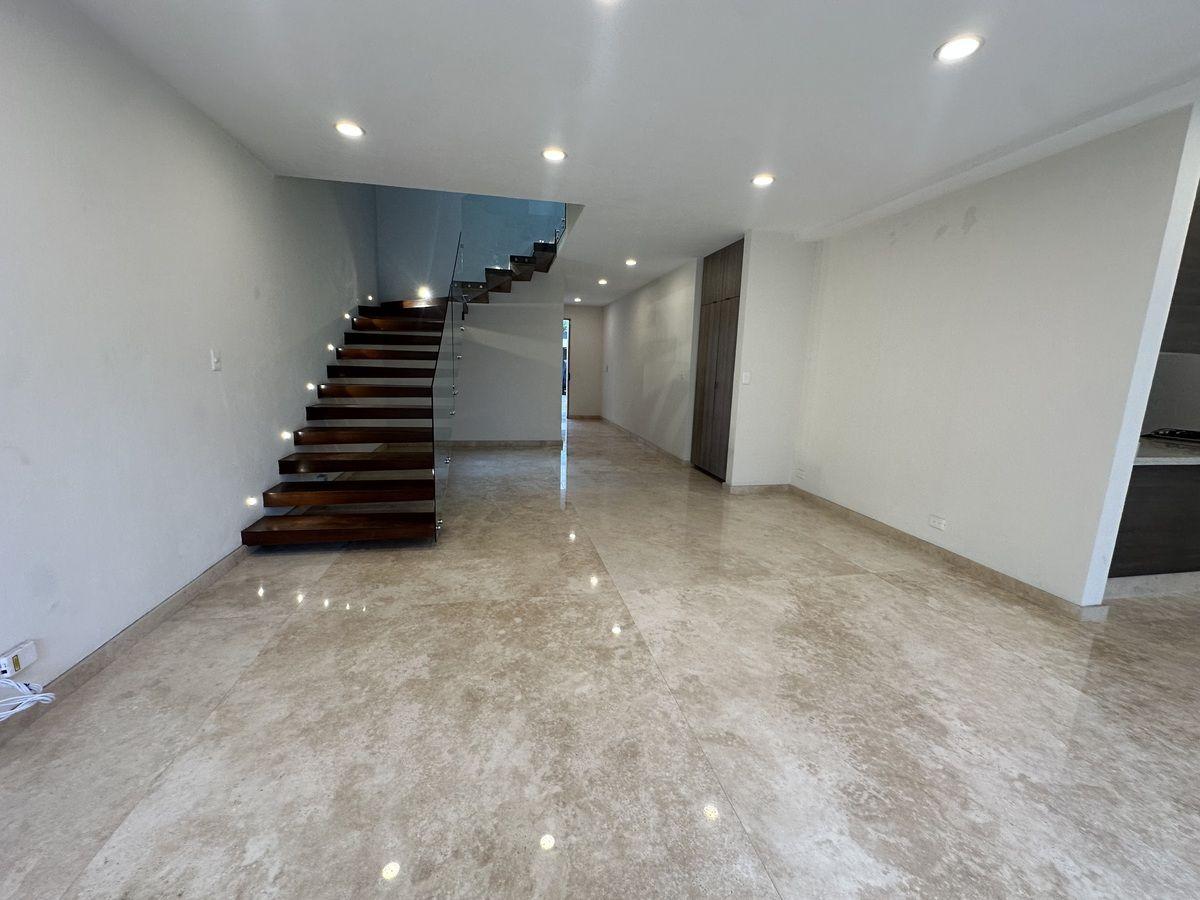 Amplia sala con pisos de mármol y una escalera de diseño moderno.