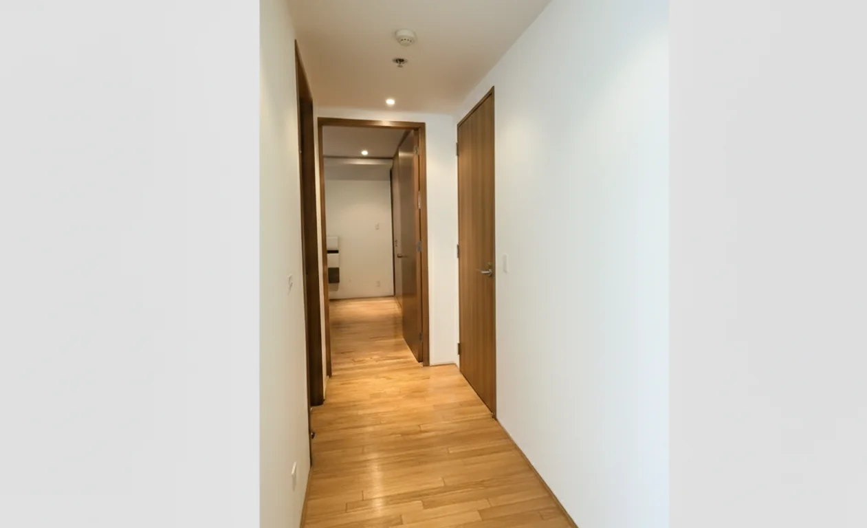 Pasillo con piso de madera que conecta las áreas del departamento.