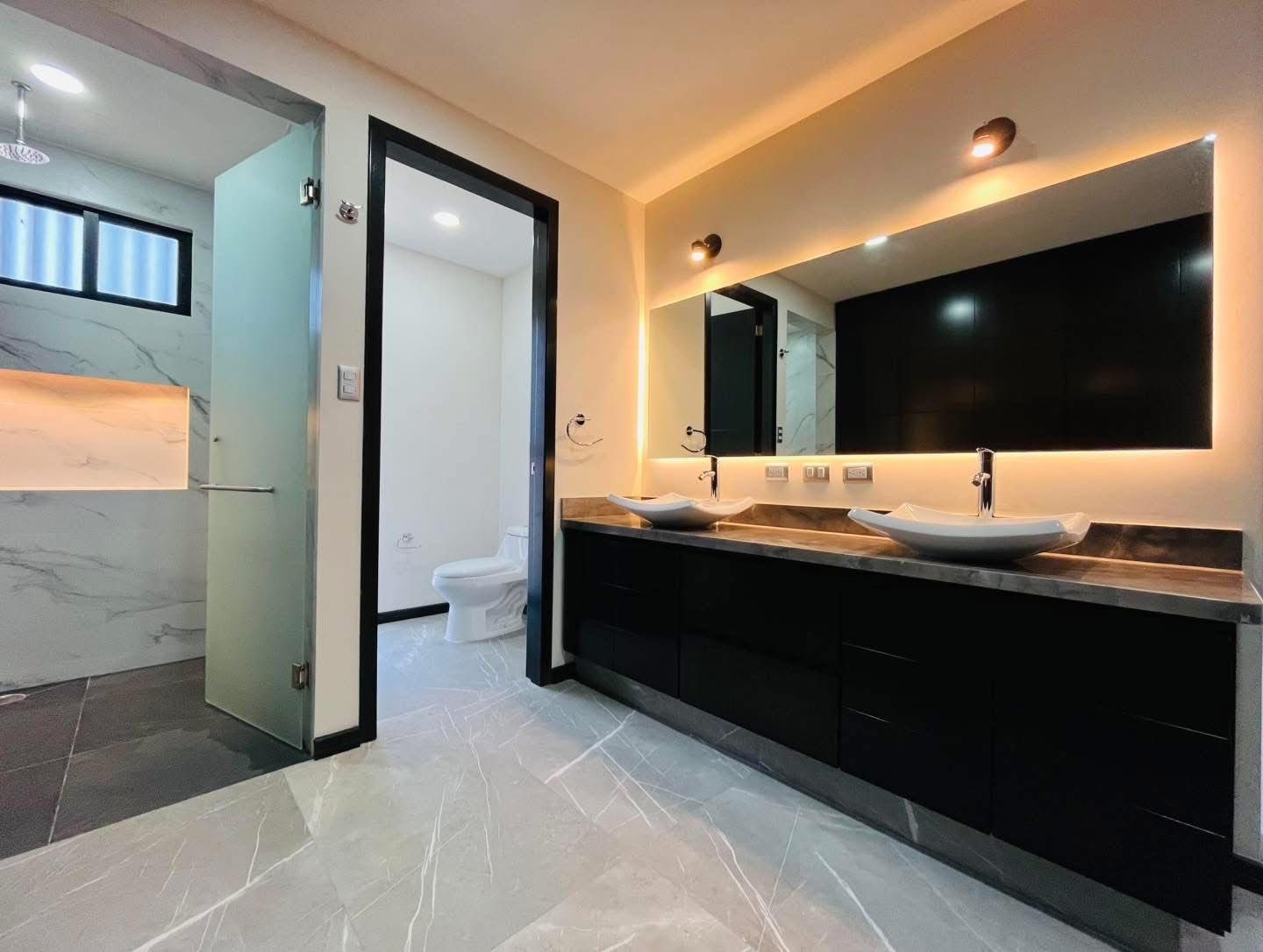 Baño moderno con acabados en mármol y detalles de iluminación.