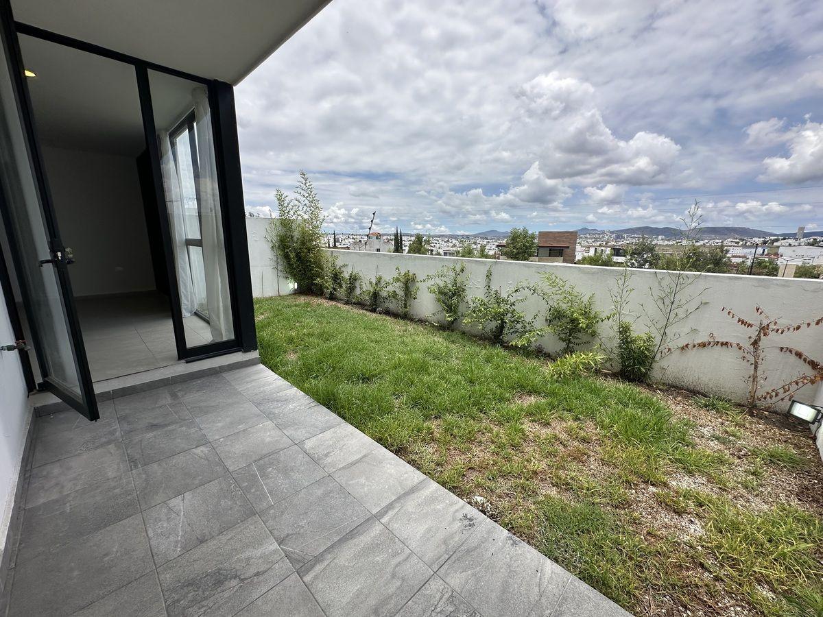 Pequeño jardín trasero con pasto y plantas decorativas.
