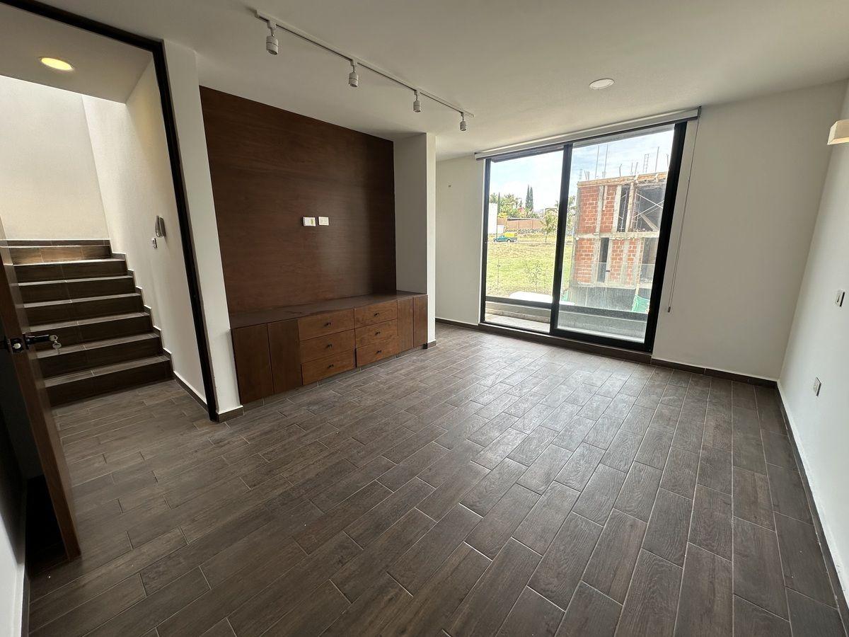 Estudio con piso de madera y ventana amplia, ideal para oficina.