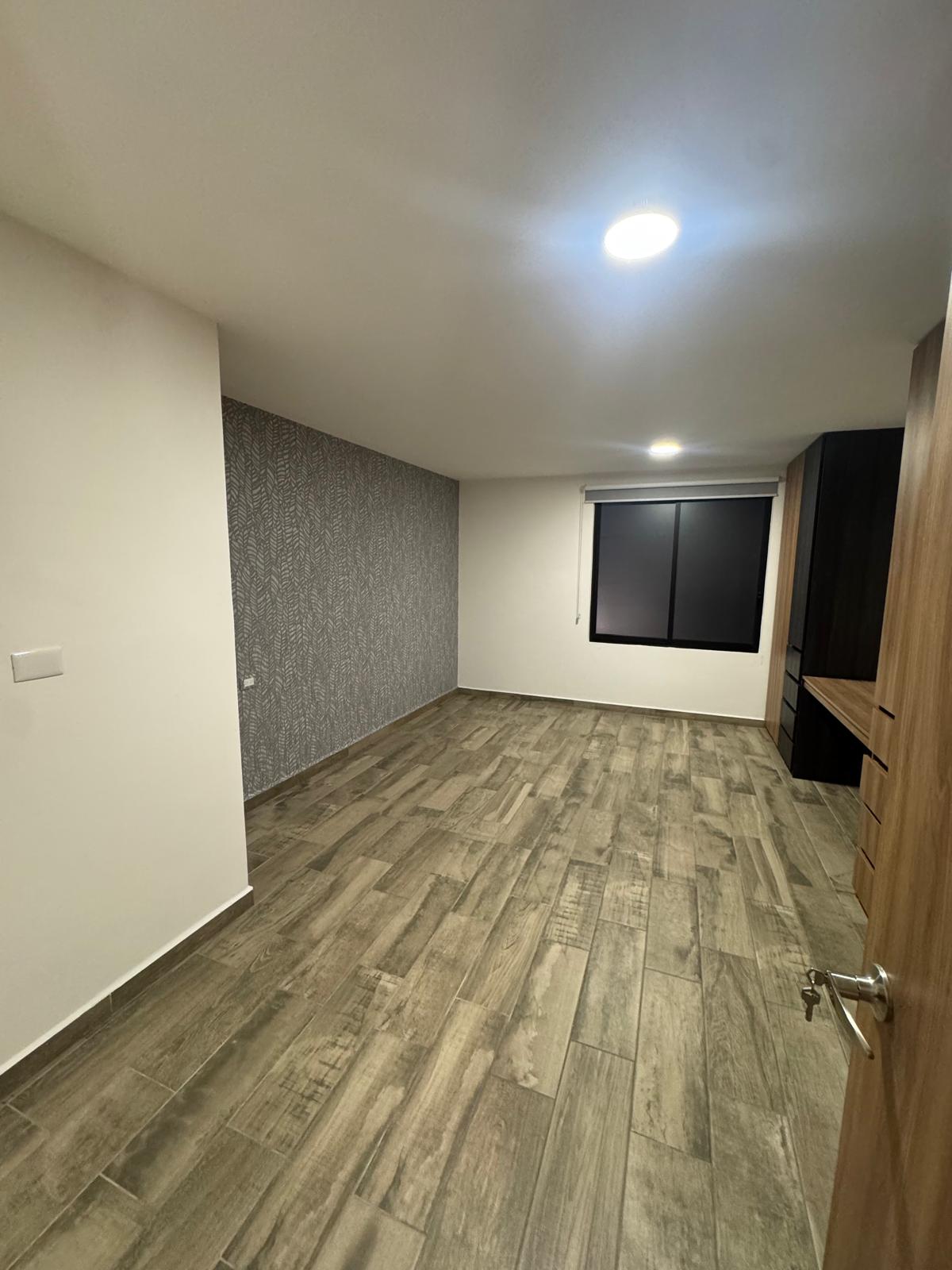 Recámara con acabado de papel tapiz en una pared, ideal para personalizar.