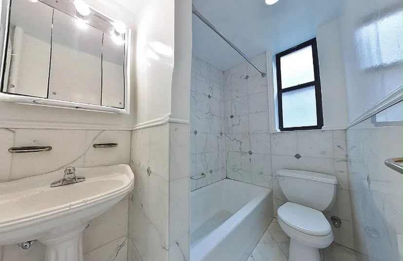Baño completo con azulejos y bañera, bien iluminado.