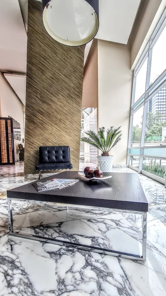 Elegante lobby con piso de mármol y mobiliario moderno.