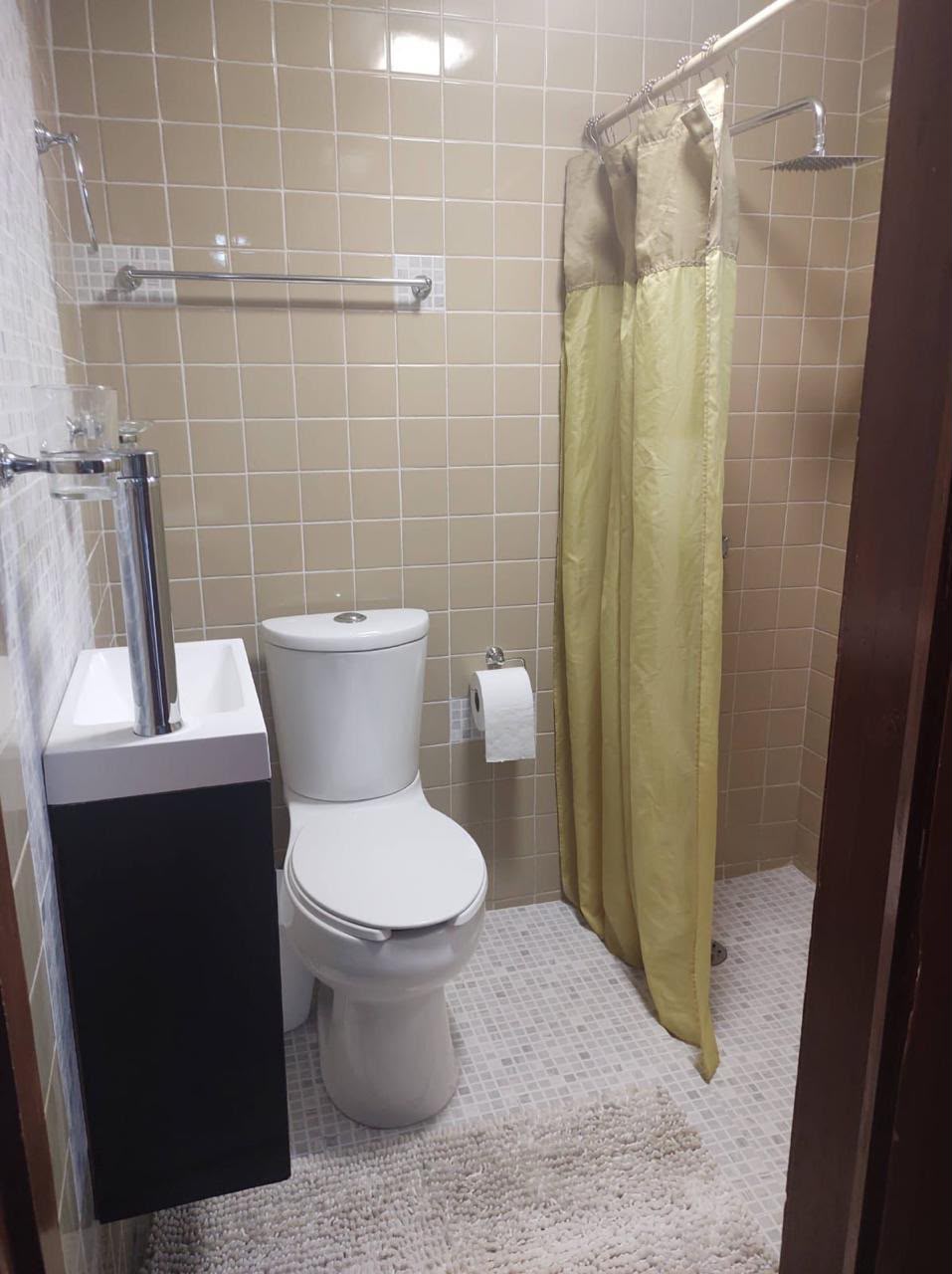 Baño con azulejos beige y accesorios modernos. Práctico y funcional.
