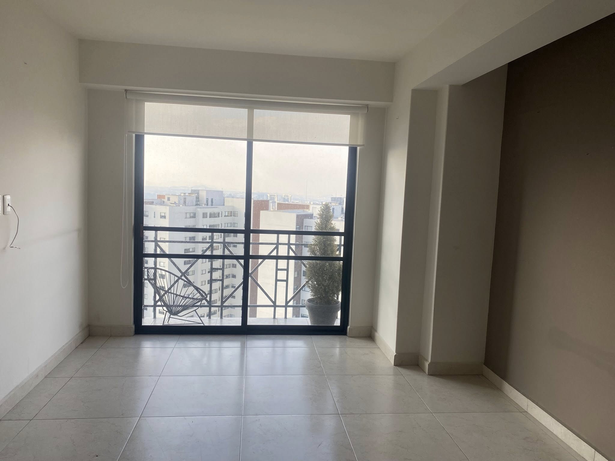 Sala con ventanal amplio y vista a la ciudad, muy iluminada.