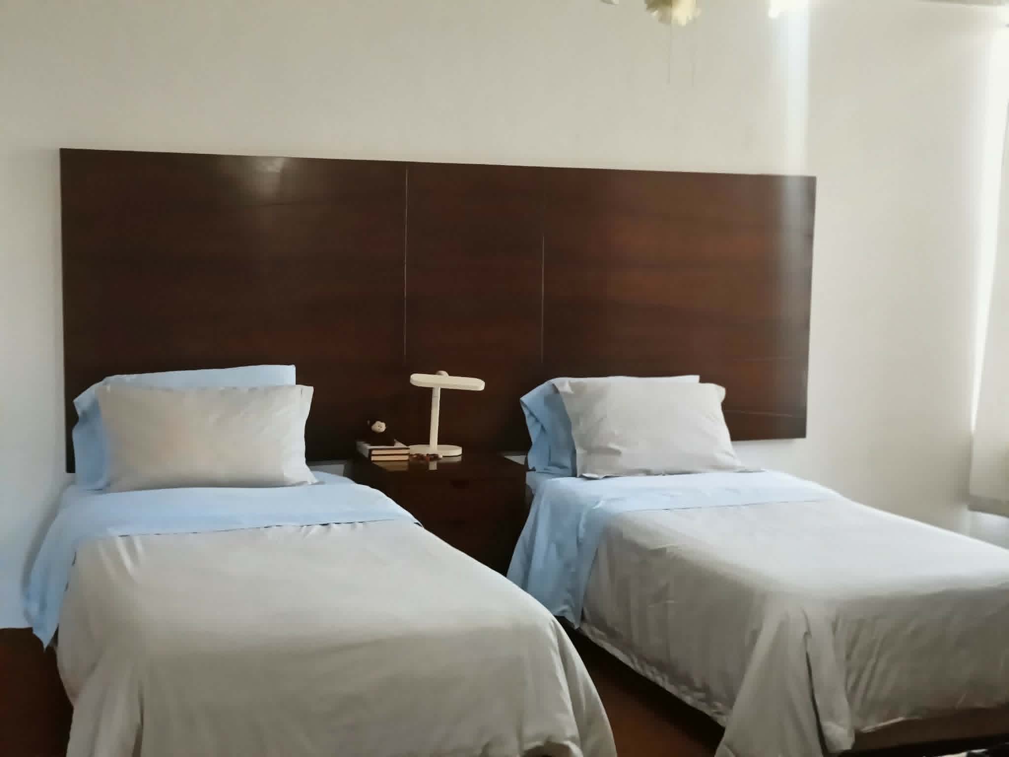 Otra vista de la habitación con dos camas individuales y buena iluminación.