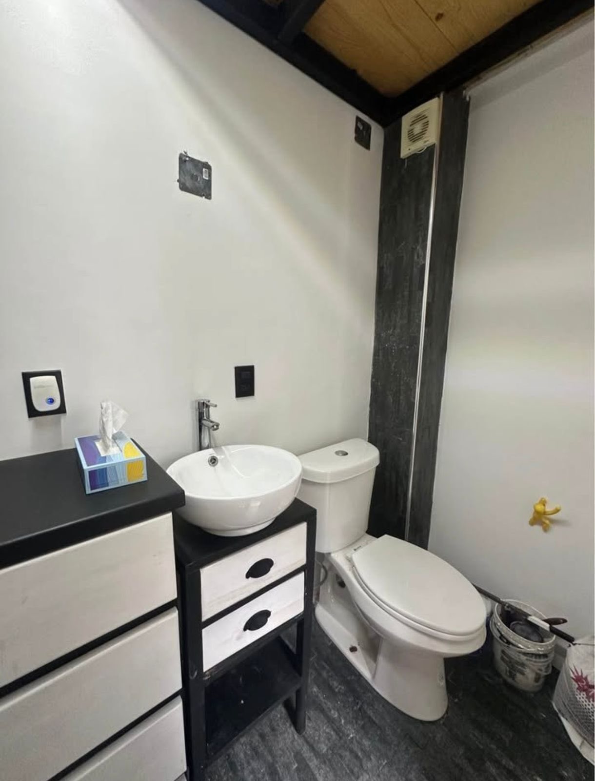 Baño moderno con lavabo sobre mueble y WC, incluye espacio de almacenamiento.