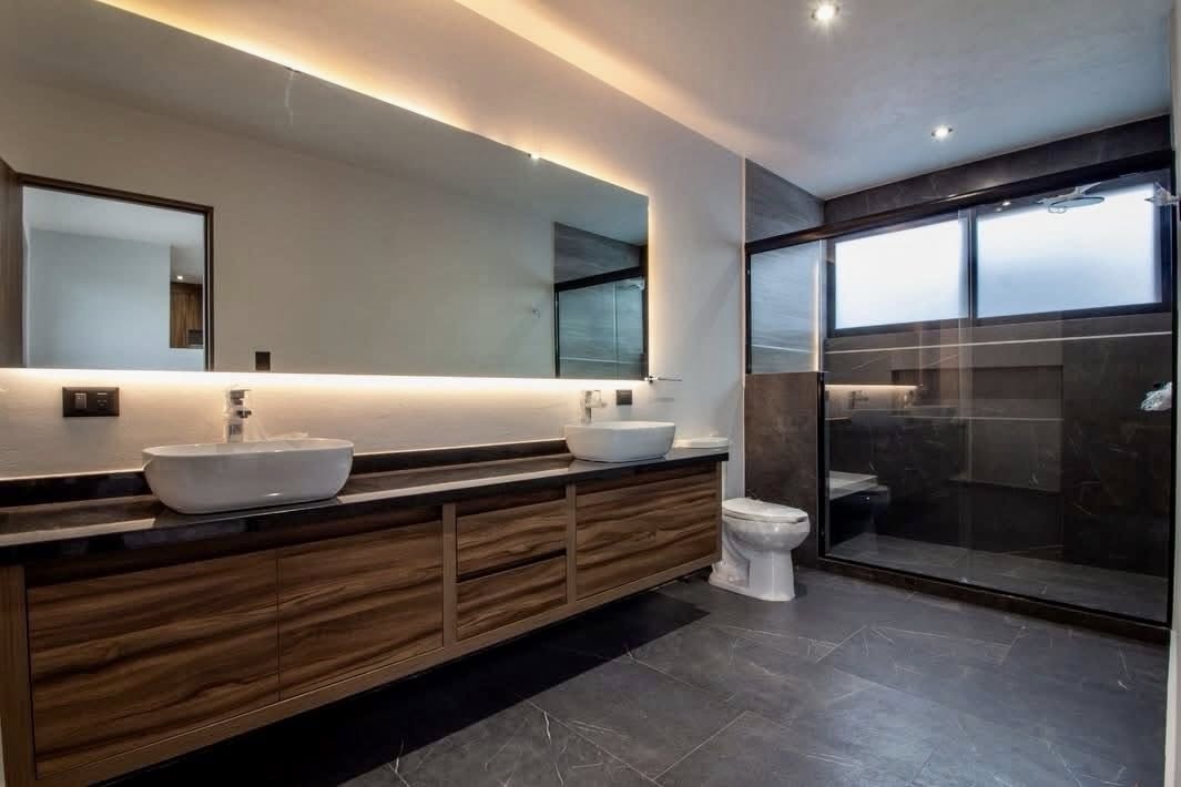 Baño principal amplio con doble lavabo y ducha de cristal.