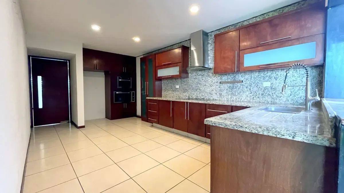 Cocina integral con acabados de granito y madera, bien equipada.