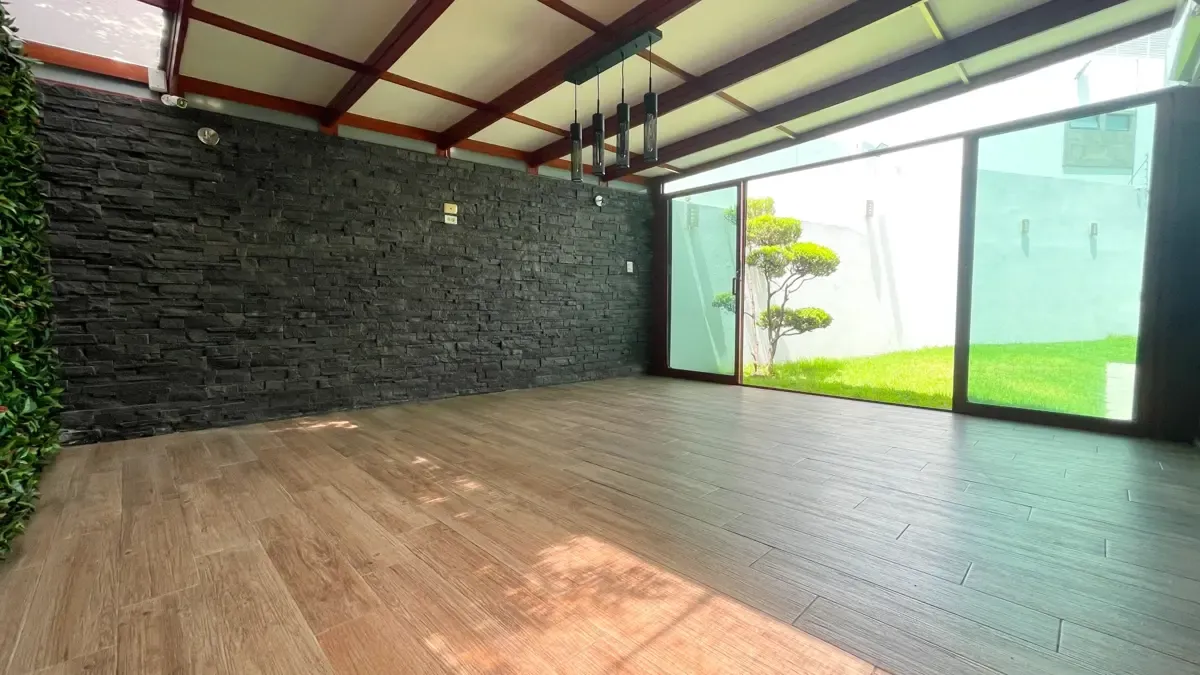 Terraza techada con piso de madera y acceso al jardín.