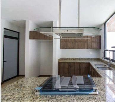 Cocina moderna con barra de granito y gabinetes de madera.