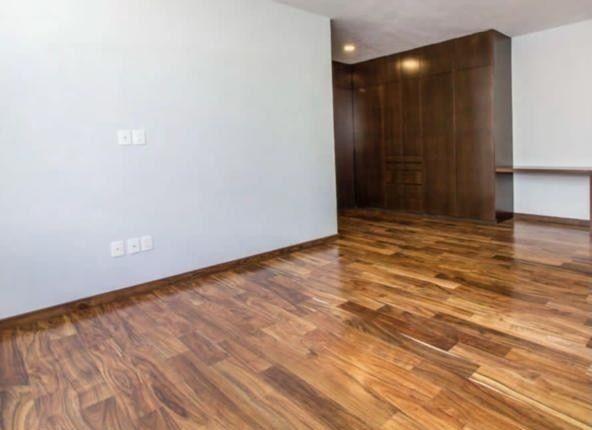 Amplia recámara con piso de madera y detalles de madera en paredes y muebles.