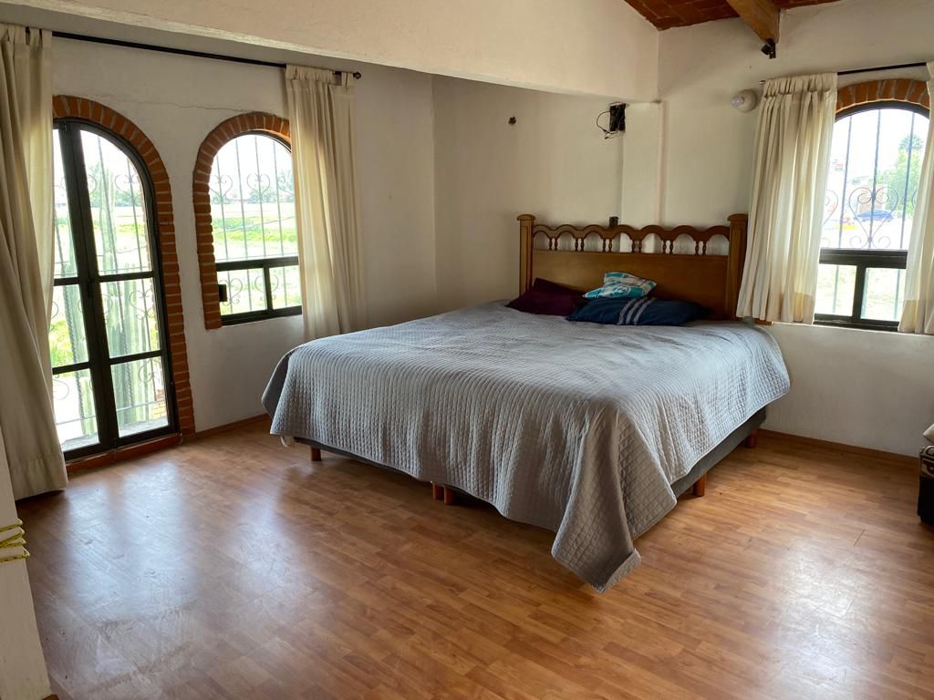 Recámara amplia con piso de madera y grandes ventanas.