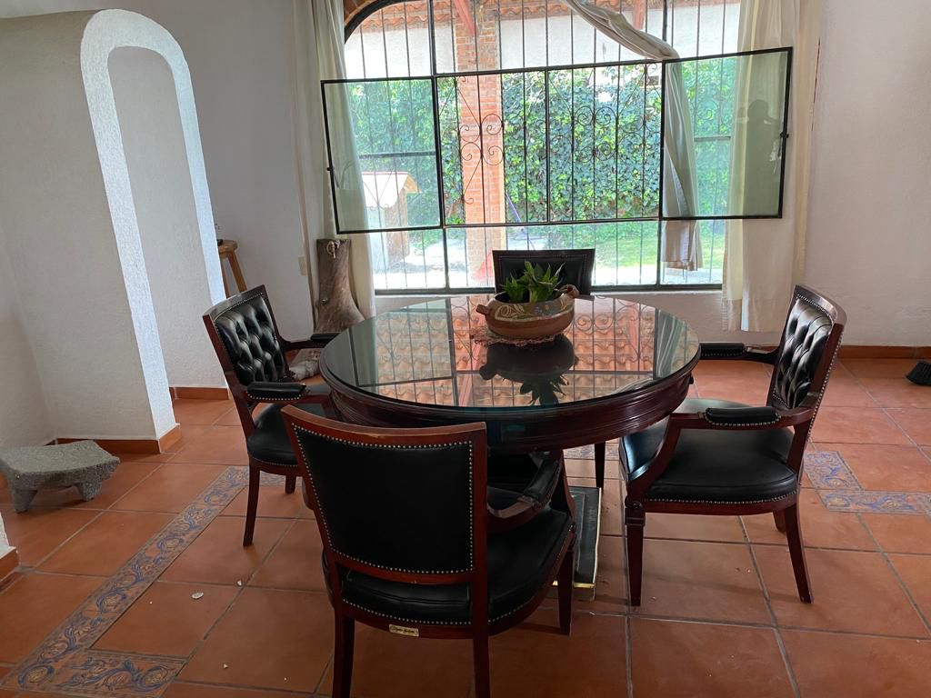 Comedor iluminado con ventanales grandes que dan al jardín.