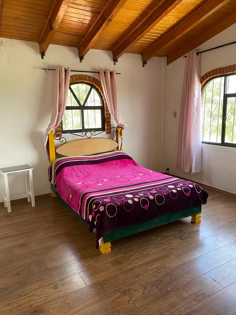 Recámara con techo de madera y ventana estilo rústico.