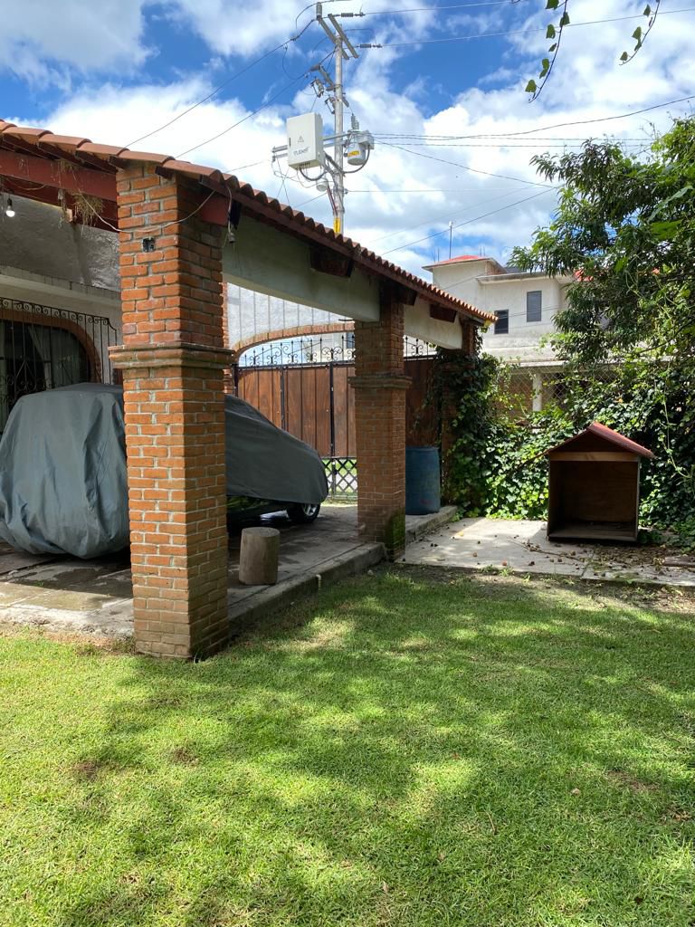Jardín amplio con área techada, ideal para estacionamiento o terraza.