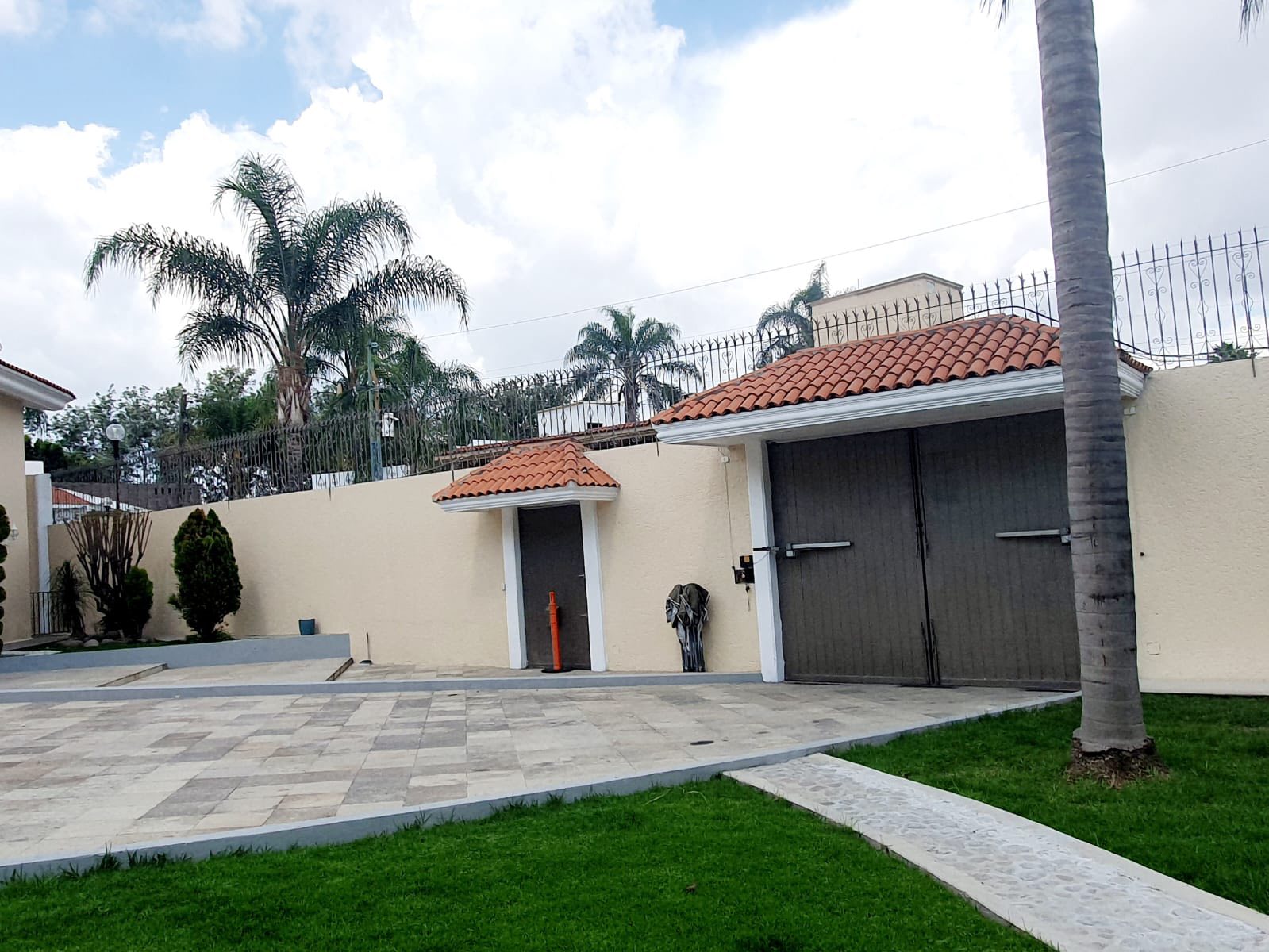 Entrada principal con portón eléctrico y espacio de estacionamiento.