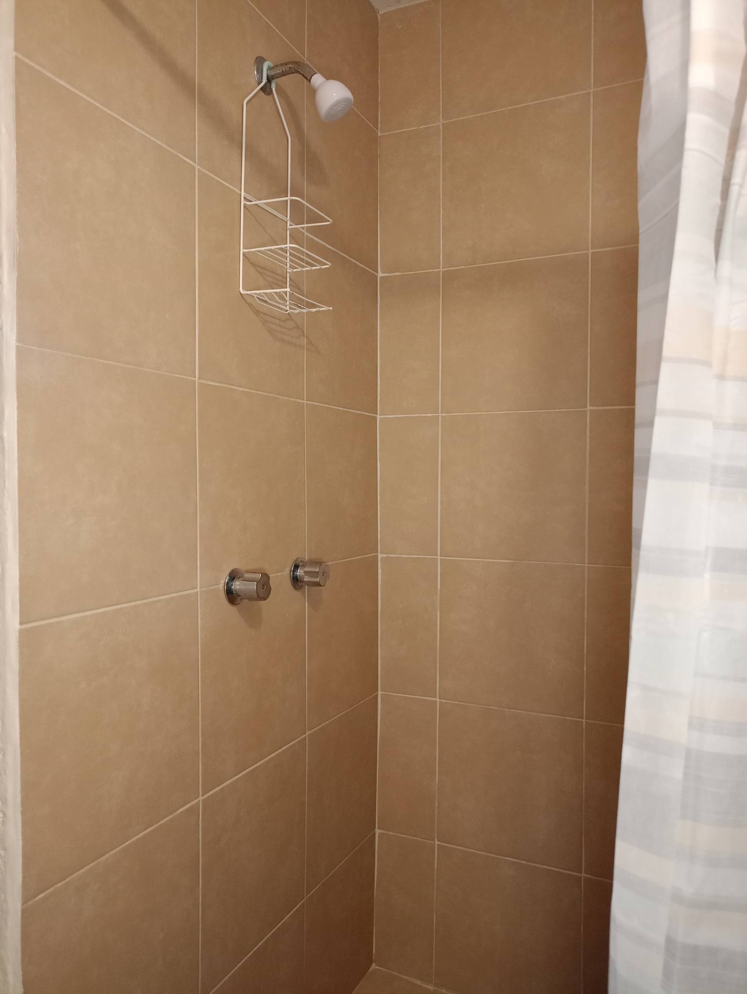Baño con regadera de cerámica sencilla.