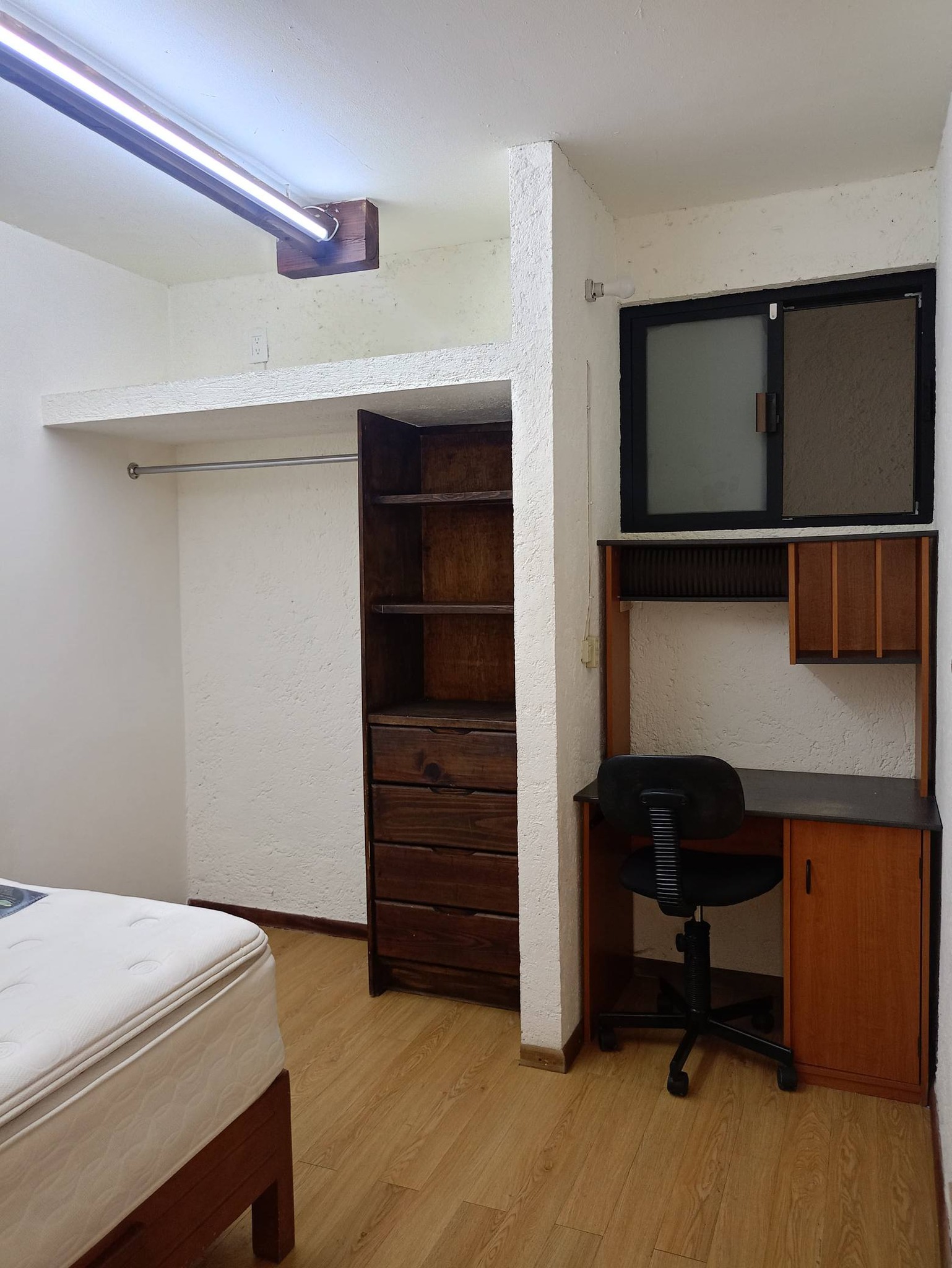 Recámara con escritorio, silla y closet de madera.