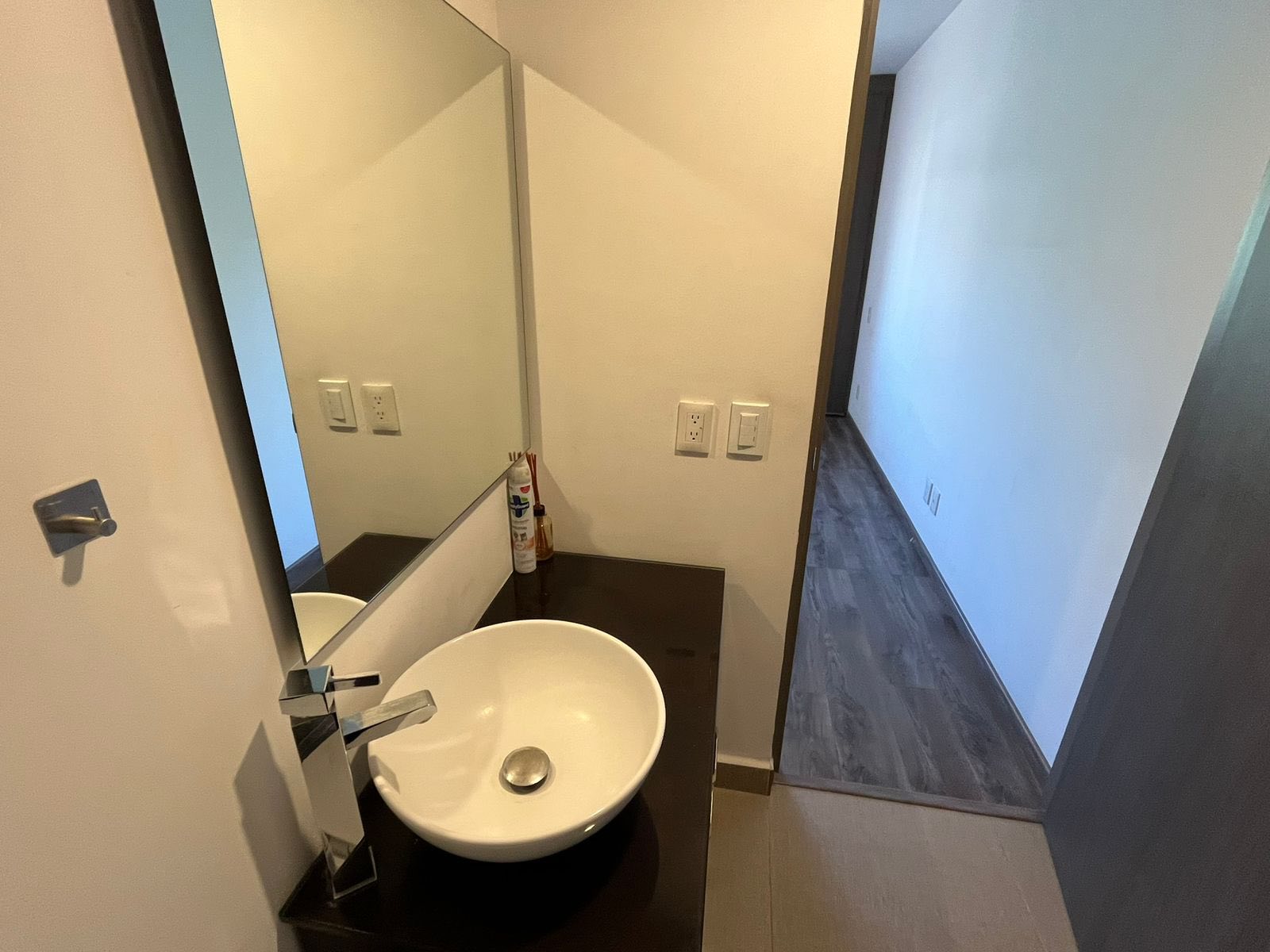 Baño con lavabo moderno y espejo amplio.