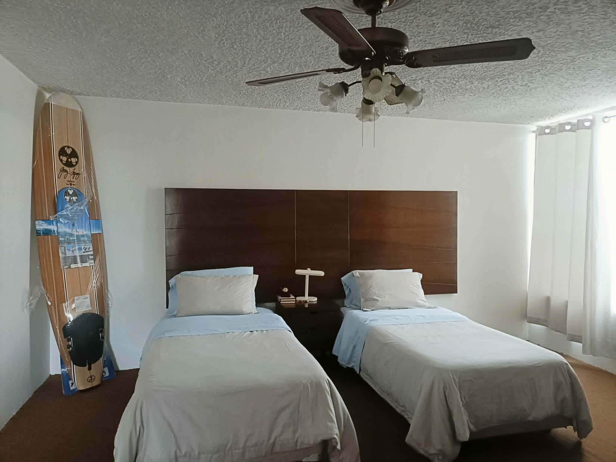 Habitación con dos camas individuales y ventilador de techo. Buena entrada de luz.