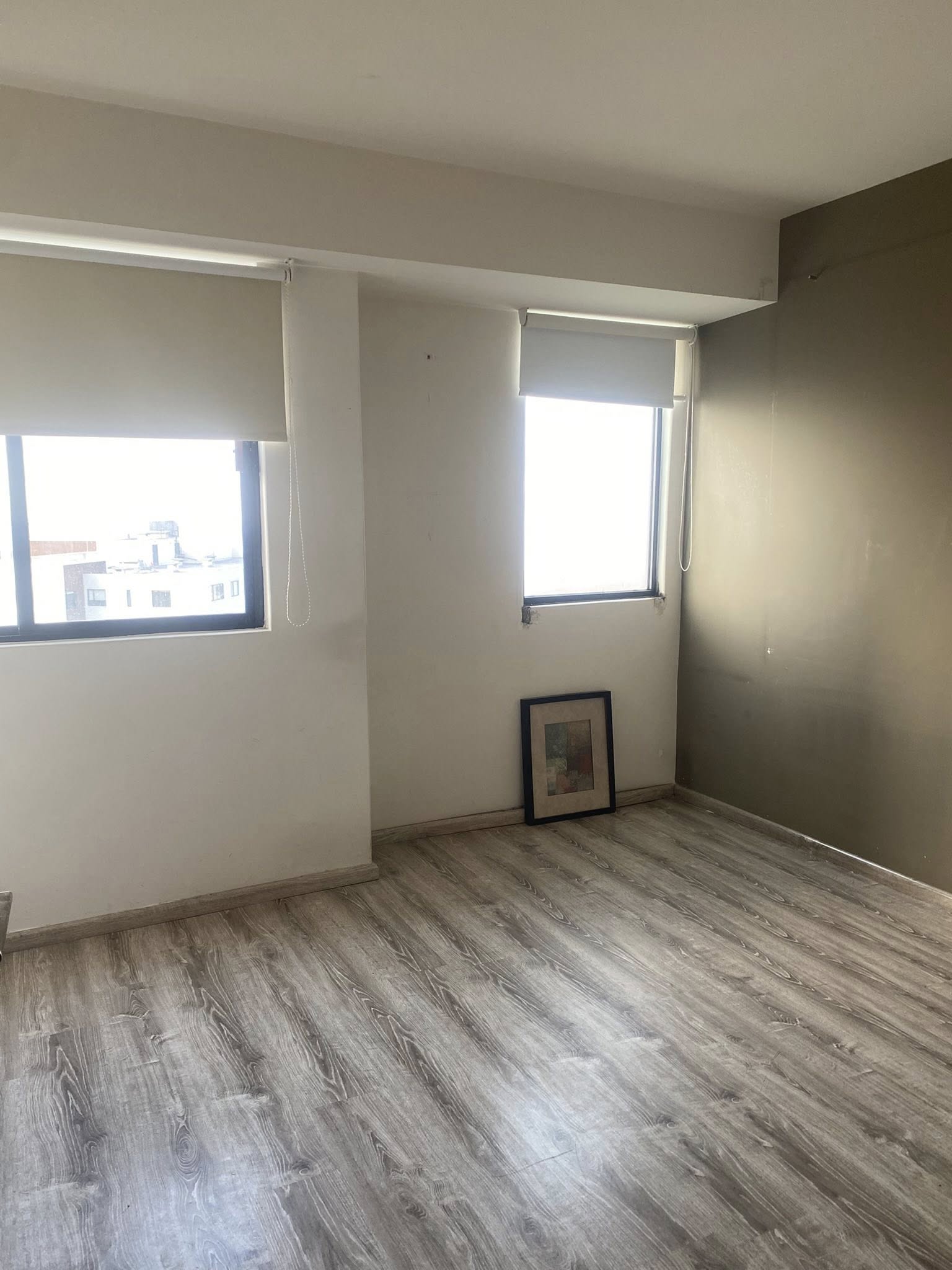 Recámara con piso laminado y ventanas que ofrecen buena iluminación.