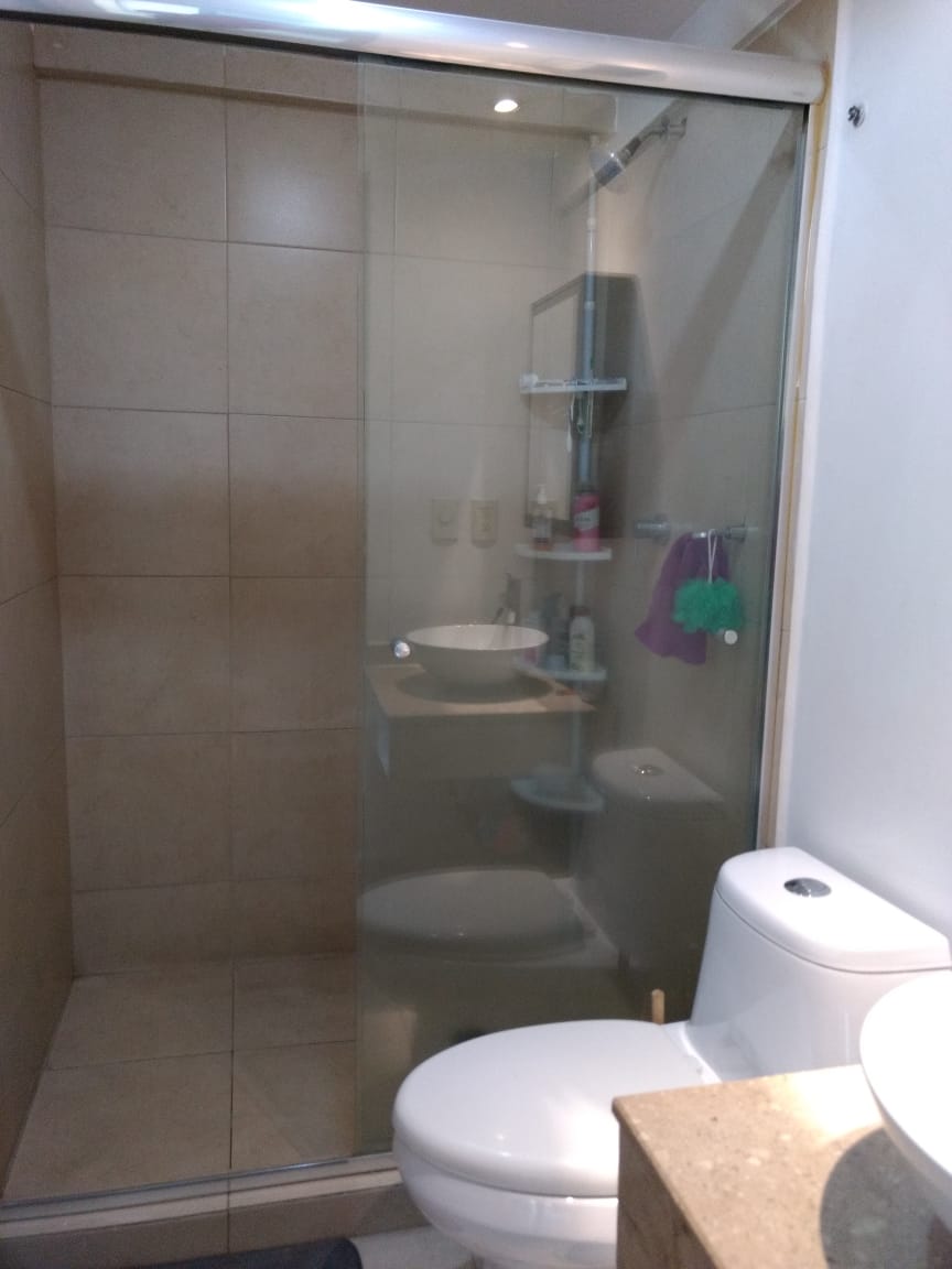 Baño con modernos acabados en cerámica y cancel de vidrio.