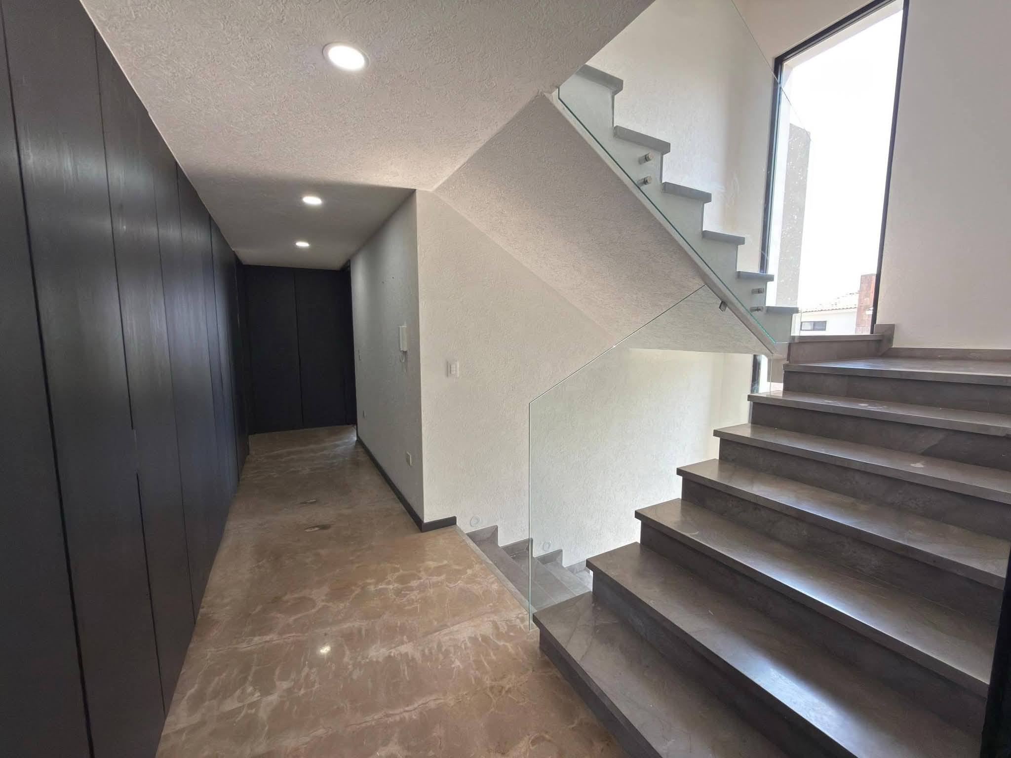 Escaleras amplias con barandal de vidrio y buena iluminación natural.